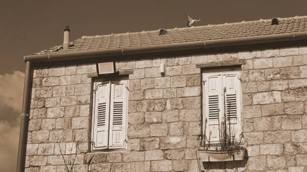 A weathered window frame in an abandoned building, showcasing peeling paint and a view of a dilapidated structure behind it