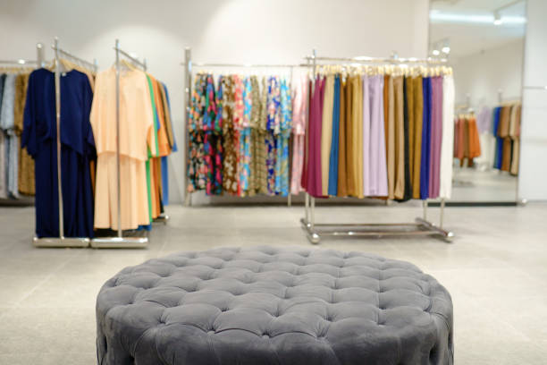 Mannequins dressed in stylish clothing are showcased in a clothing store within a shopping mall, with a focus on fashion and retail.