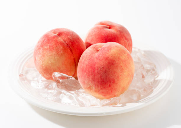 istock Cut peaches and ice on a plate on white background. 2171271868