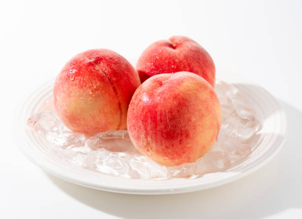 istock Cut peaches and ice on a plate on white background. 2171271871