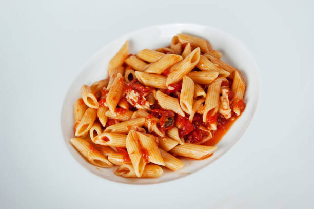 penne with tomato sauce with green herbs in white plate