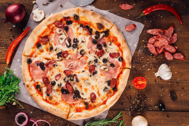 istock Delicious pizza lying on wooden table surrounded by fresh ingredients 2171272774