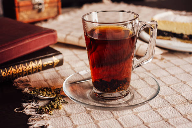 istock Steaming cup of tea with books and dessert on tablecloth 2171273734