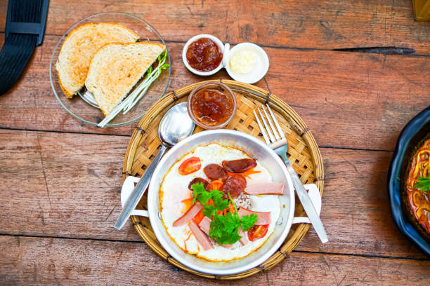 The unique characteristic of the Pan Fried Egg is that the container it is served in is a small, flat pan with two handles. To make Pan Fried Egg, you fry the egg in the pan and then sprinkle it with pork sausage, Chinese sausage, minced pork, or other side dishes as desired. To eat Pan Fried Egg deliciously, it must be served hot, sprinkle with pepper and seasoning sauce as desired, and eat with bread, along with hot tea, coffee, or Ovaltine.