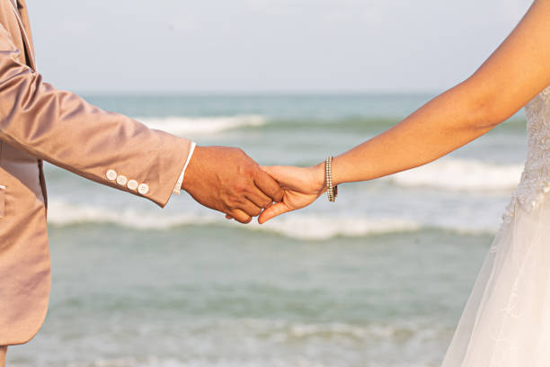 istock Bride and groom's hands holding hands, sea background hand focus 2171274686