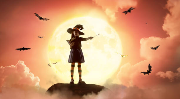 Happy little girl in witch costume at Halloween. Kid on moon sky background.