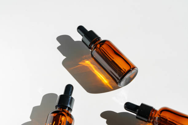 istock Arranged Amber Glass Bottles With Droppers on White Surface Accentuated by Shadows in Bright Light 2171277756