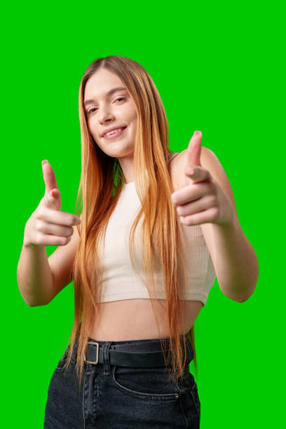 istock Smiling Young Woman Pointing at Camera With Green Screen Background 2171280036