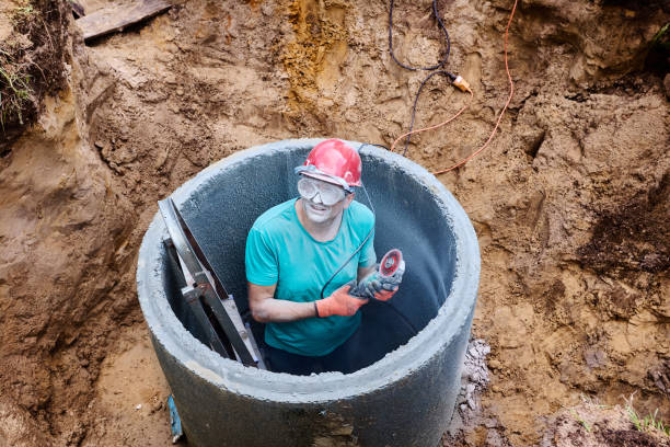 istock Homeowner uses diamond circular saw to create hole for sewer pipe while installing septic tank. 2171284176