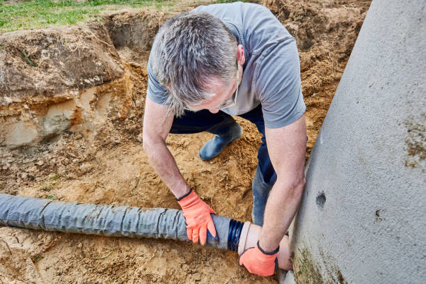 istock Worker connects perforated drain pipe to septic tank through which wastewater flows into leach field. 2171284261