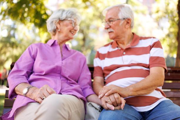istock An elderly couple holding hands on a park bench 2171284367