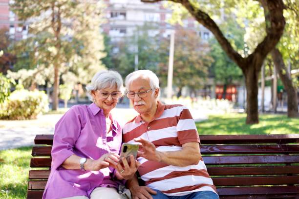 istock Modern senior couple having a video call while sitting on the bench in the park 2171285826