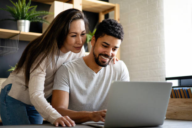 istock Happy interracial couple smiling while working or having fun at laptop 2171286863