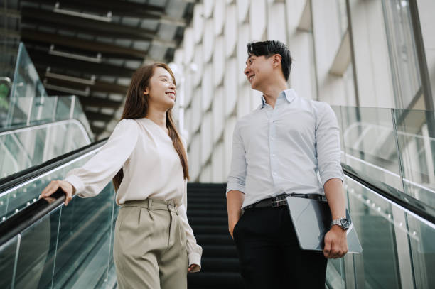istock Two Asian Chinese business people talking on escalator. 2171287485
