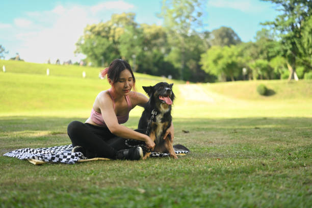 istock Young woman resting after workout in a park, playfully interacting with her dog 2171288086