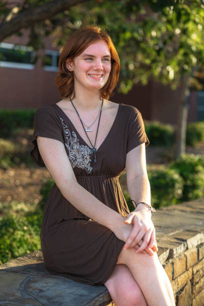 istock Young woman smiling on a stone bench in a sunny park. 2171290192
