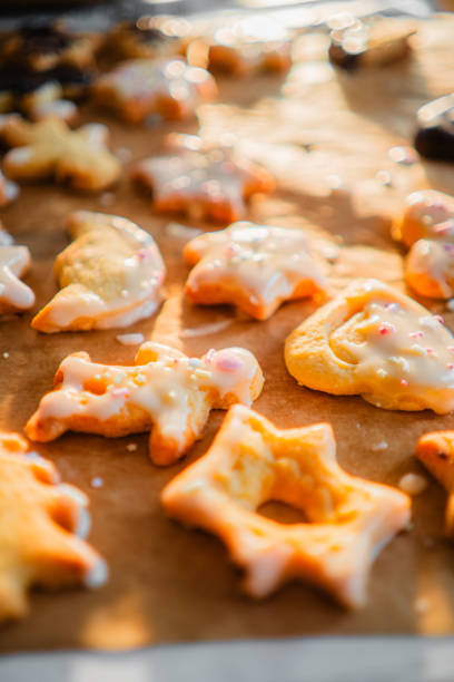 Baking Paper with Batch of Freshly Baked Biscuites with Sugar Coat and Springles in Different Forms for Christmas Extreme Close Up
