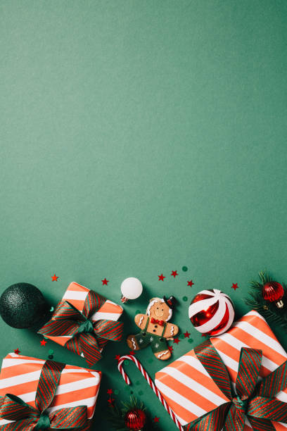 istock Christmas vertical flat lay with vintage Xmas decorations, fir branches, striped gift boxes and baubles on dark green background. 2171293657