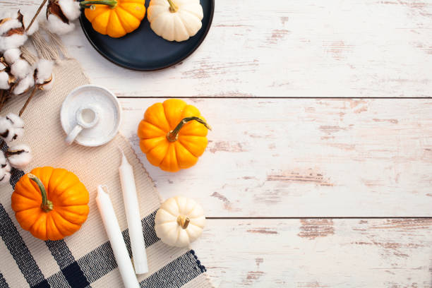 istock Autumn flat lay composition. Top view pumpkins, candles, checkered plaid, cotton branches, checkered plaid on rustic wooden table. 2171294813