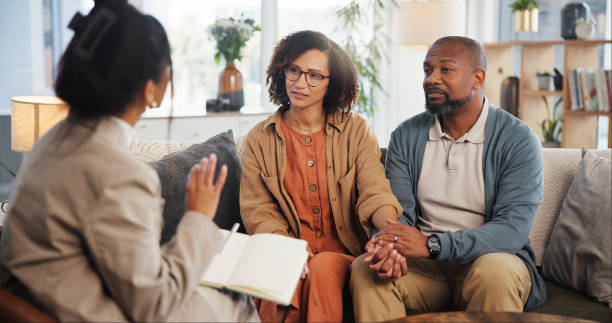 istock Couple, therapy and holding hands with discussion on sofa for guidance, communication and advice. Consultation, service and therapist with book in office for marriage counseling, support and progress 2171295029