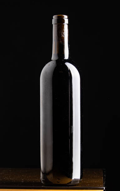 Botellas de vino oscuro con sombras dramáticas, ideal para retoque