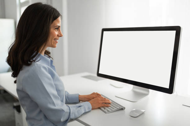 istock Young female employee working on computer at standing desk, mockup screen on computer 2171297138