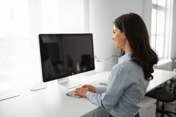 istock Young female employee working on computer at standing desk 2171297143