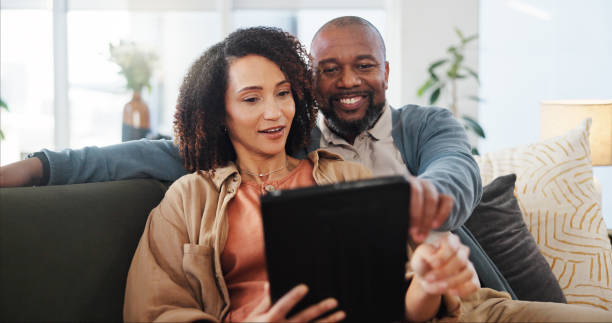 istock Couple, relax and discussion with tablet on sofa for online order, communication and decision on lunch. Interracial, man and woman with technology at home for takeout app, choice and food delivery 2171298070