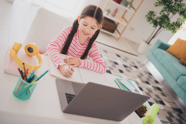 istock Photo of young child brunette girl studying remote using computer during lecture lesson writing homework at home isolated in her room 2171298392