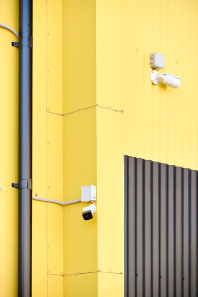 istock CCTV camera. Security camera on Aluminum composite panels for repair restore facade of commercial building warehouse barn wall, two CCTV on buildings monitoring the street. 2171301296