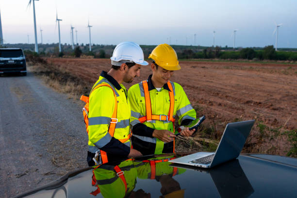 istock Diverse ethnicity male technicians working in the wind turbines field. Innovation engineer men use laptop computer work to develop environmental renewable clean energy outdoors at windmill power farm. 2171307947