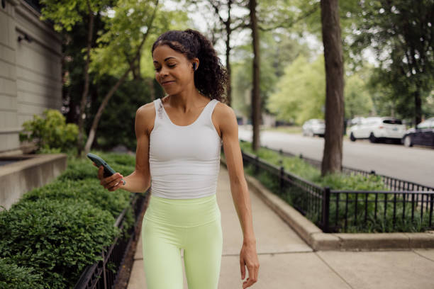 Smiling black athlete using cell phone on the move.