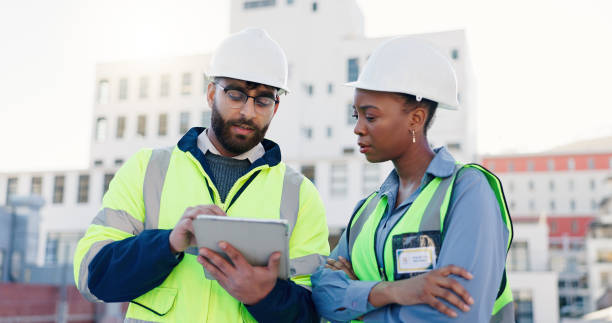 istock Business people, civil engineer and discussion with tablet on rooftop for construction or planning in city. Contractors, colleagues or architects with technology for industrial infrastructure in town 2171314746