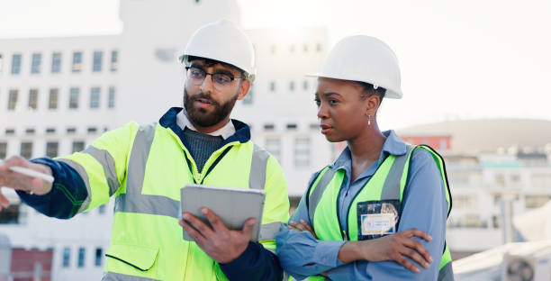 istock Business people, architect and planning construction with tablet on rooftop for building maintenance in city. Contractors, colleagues or civil engineers with technology for infrastructure in town 2171314747
