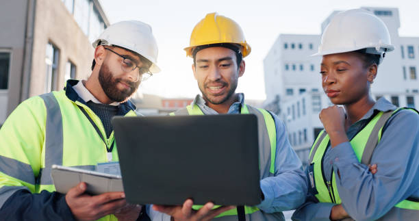 istock Tablet, laptop and construction engineers on site for city planning, maintenance or repairs. Discussion, contractor and team of civil employees with technology for renovation approval on town rooftop 2171314798