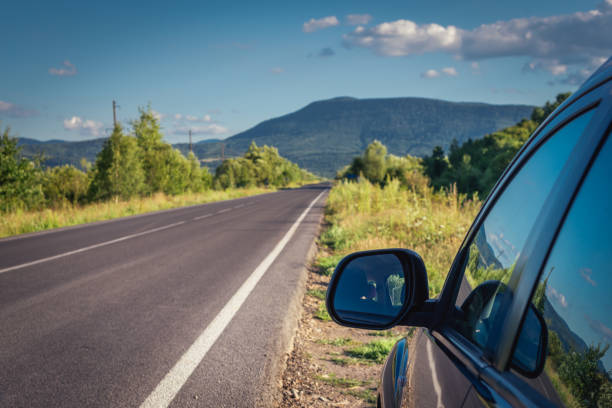 In the summertime, under the sunny sky, a car drives along the country road, creating a mesmerizing motion blur effect. As it speeds ahead, the surrounding environment becomes a blur of colors and shapes. Trees pass by in a rural landscape, accentuating the sense of a long journey. This exhilarating travel experience captures the thrill of speed and the allure of the open road.
