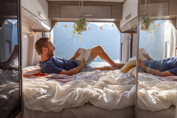 istock Man reading book in camper van with scenic lake view 2171315811