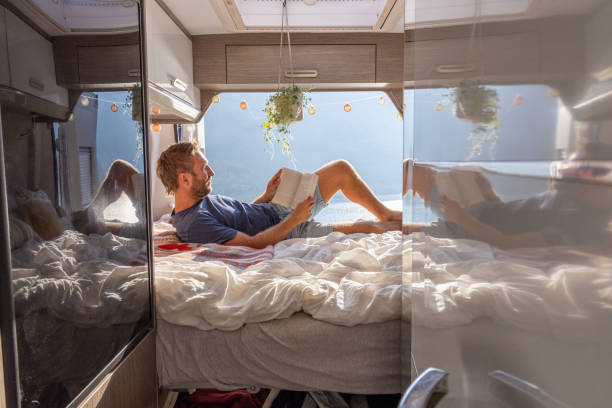 istock Man reading book in camper van with scenic lake view 2171315817