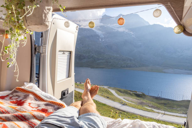 istock Man relaxing in camper van bed with lake and mountain view 2171316021