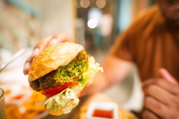 Man eating falafel burger in a vegan cafe