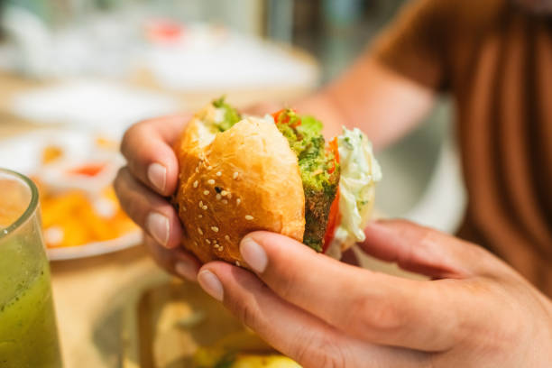 istock Man eating falafel burger in a vegan cafe 2171322969