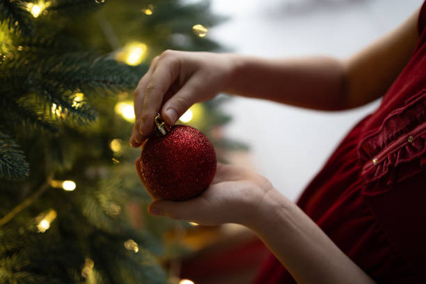 istock Child decorating Christmas tree with sparkling red ornament at home 2171323045