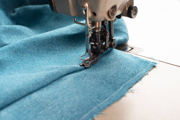 istock Industrial sewing machine with blue fabric, working place, manufacture for clothes, handmade, small local business, textile industry 2171330330