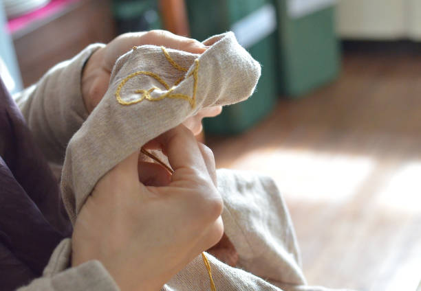 istock Hands sewing fabric indoors in natural light setting 2171330403