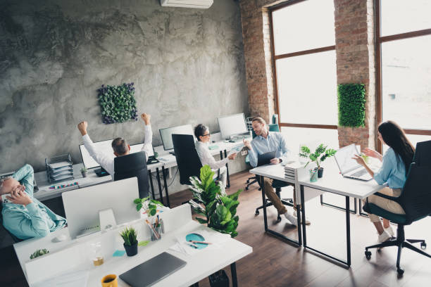 Multiethnic startup business team on meeting in a modern bright open space coworking office. Brainstorming, working on laptop. Group of coworkers walking around in motion blur.