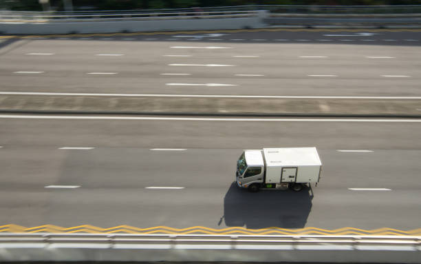 White truck traveling on highway road, with surroundings blurred indication motion.