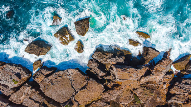Stunning rocky coastline with rugged cliffs meeting crystal-clear turquoise waves, creating a picturesque seascape