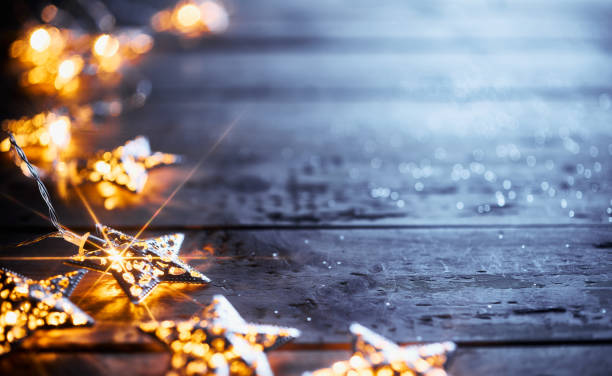 istock Twinkling star-shaped lights on rustic wooden surface with scattered glitter for festive decoration. 2171334070