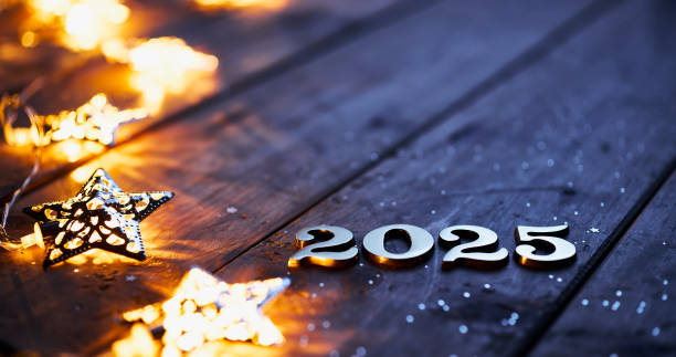 istock Illuminated 2025 numbers on wooden surface with glowing star-shaped lights and scattered festive glitter. 2171334093