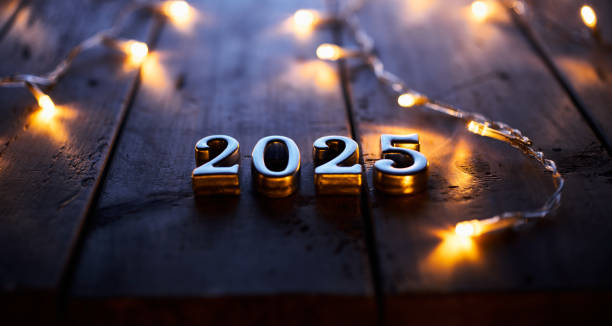 istock Glowing 2025 metallic numbers placed on a rustic wooden table surrounded by festive string lights. 2171334112